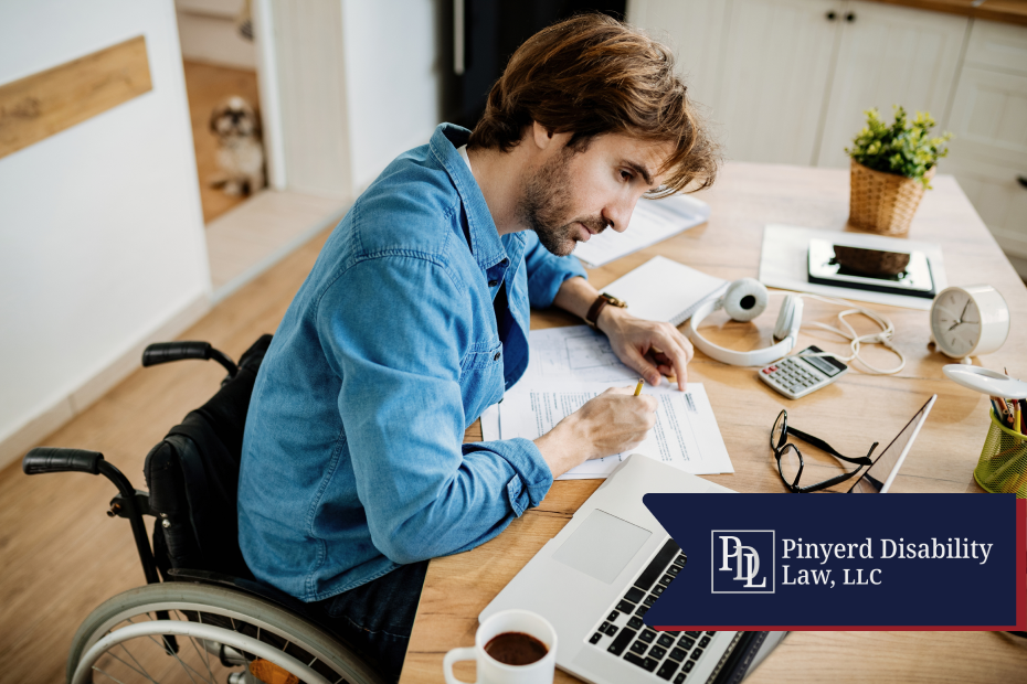 Man in a wheelchair filling out paperwork at his desk