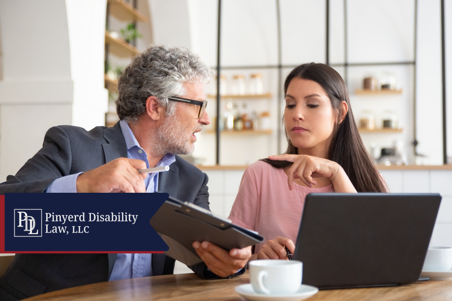 Attorney explaining paperwork to a client with a laptop on the table