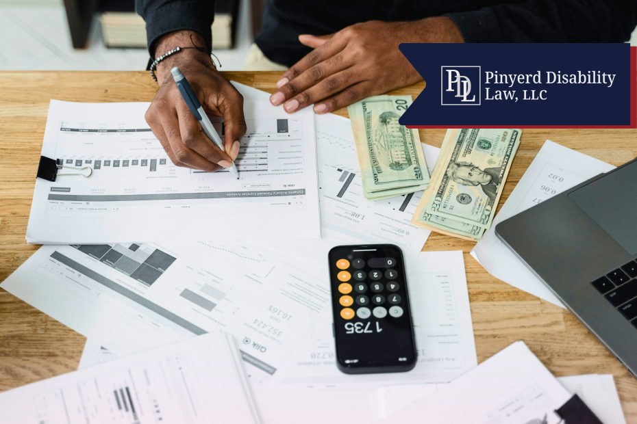 Person writing on financial papers with a calculator app and cash on the table
