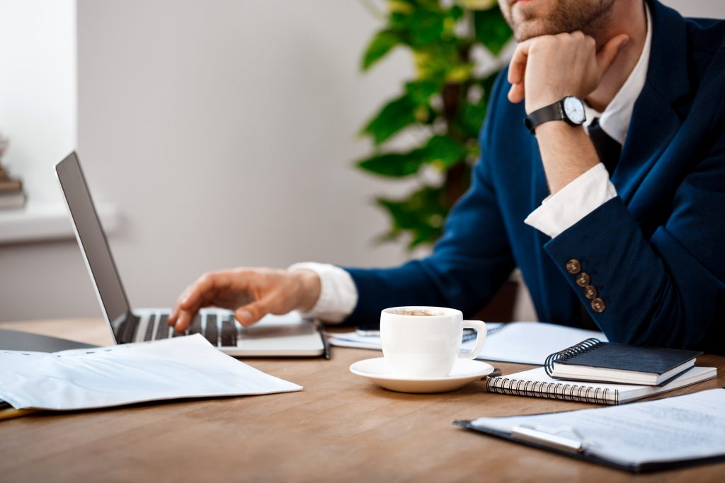 Business owner working at a laptop next to a cup of coffee