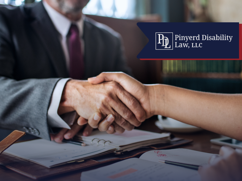 Handshake between two people at a desk with notebooks