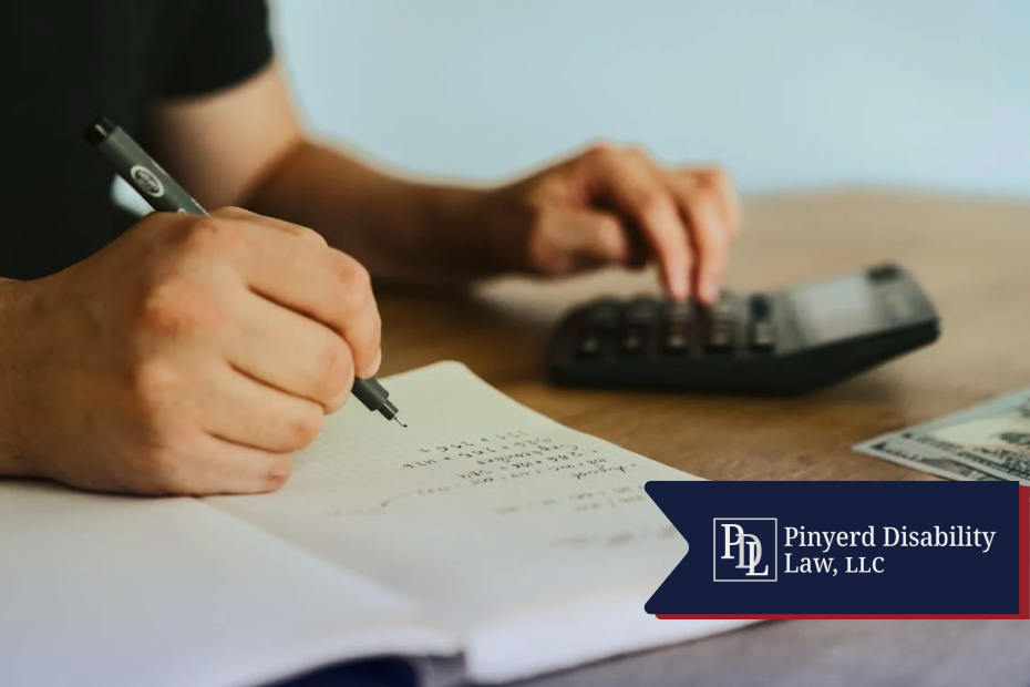 Hands writing in a notebook next to a calculator